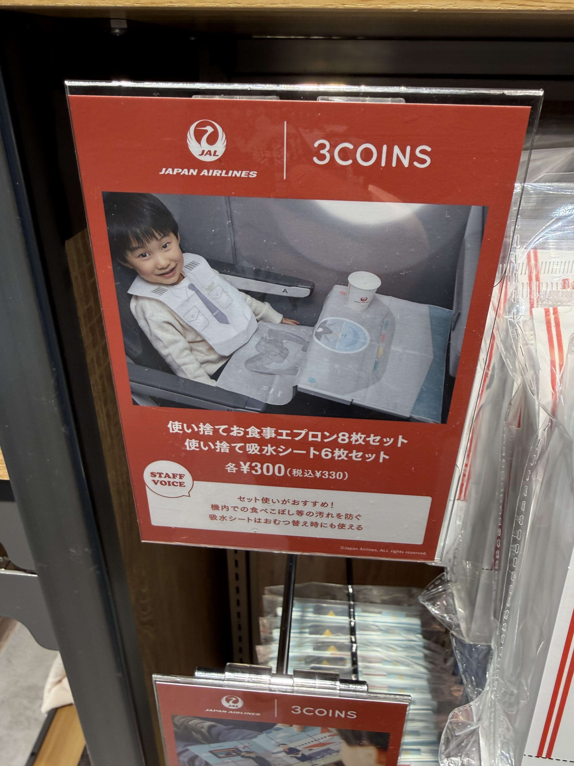 3COINSとJALコラボのPOP。パイロット柄エプロンをつける男の子の写真。