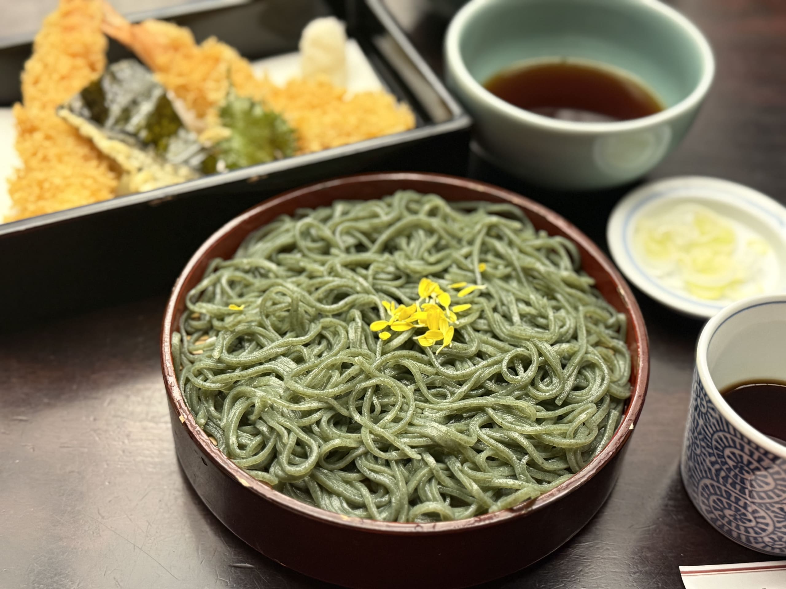 Green kusakiri soba with yellow petals and tempura.