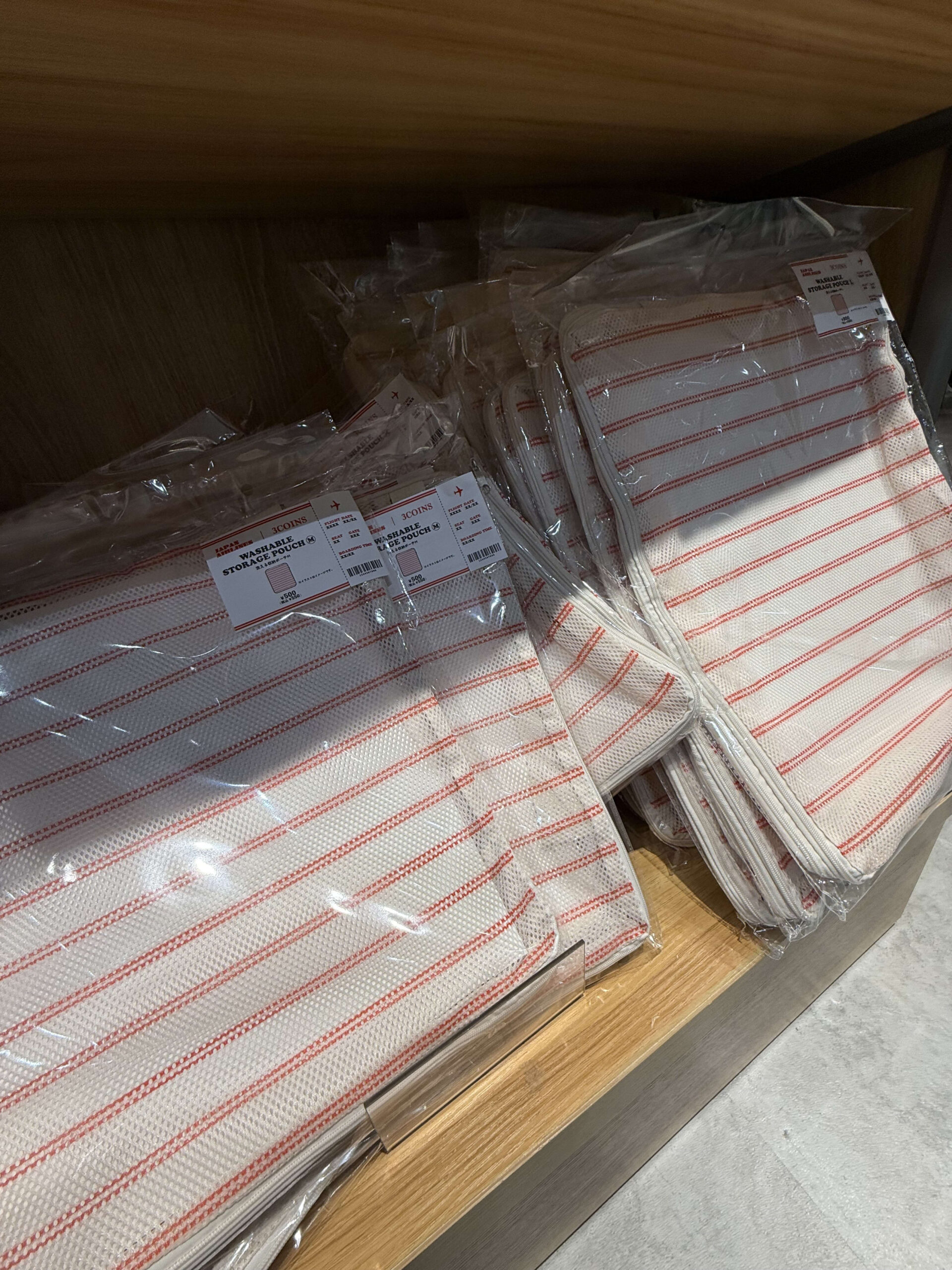 3COINSの棚に並ぶJALコラボの洗える収納ポーチ。