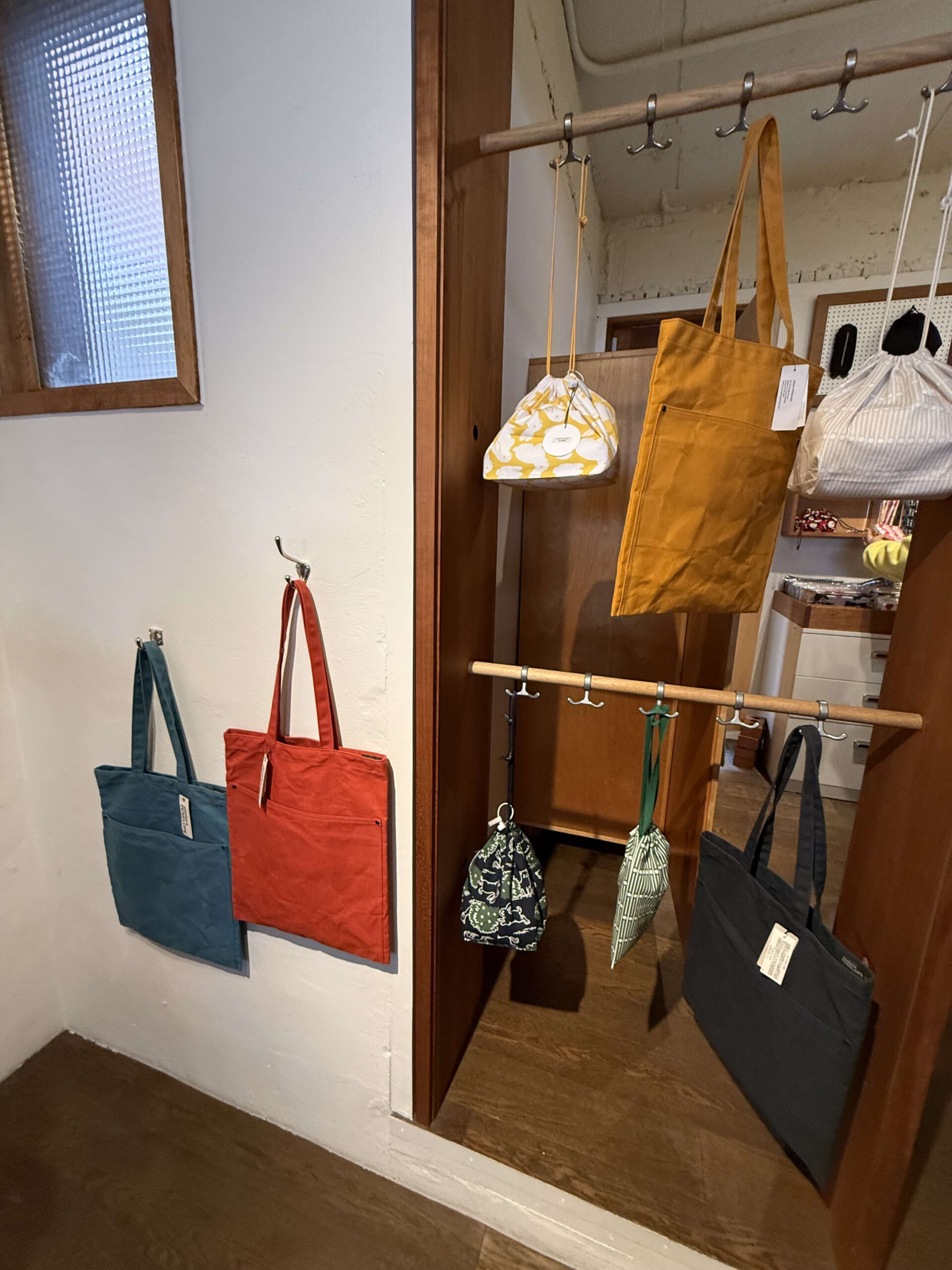 Colorful tote bags on a wooden rack.