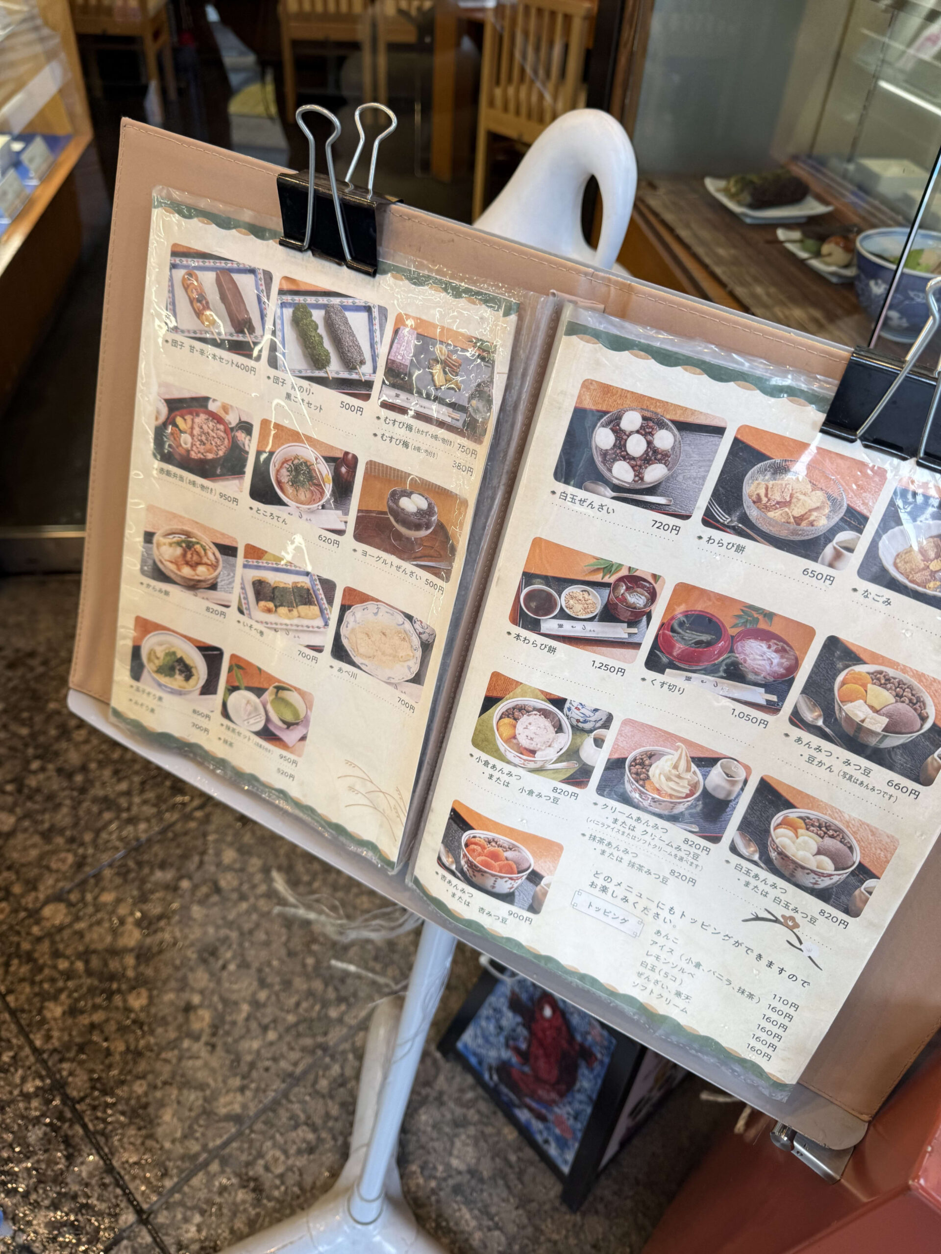 雨に濡れた石畳に立つ和菓子店のメニュー表。