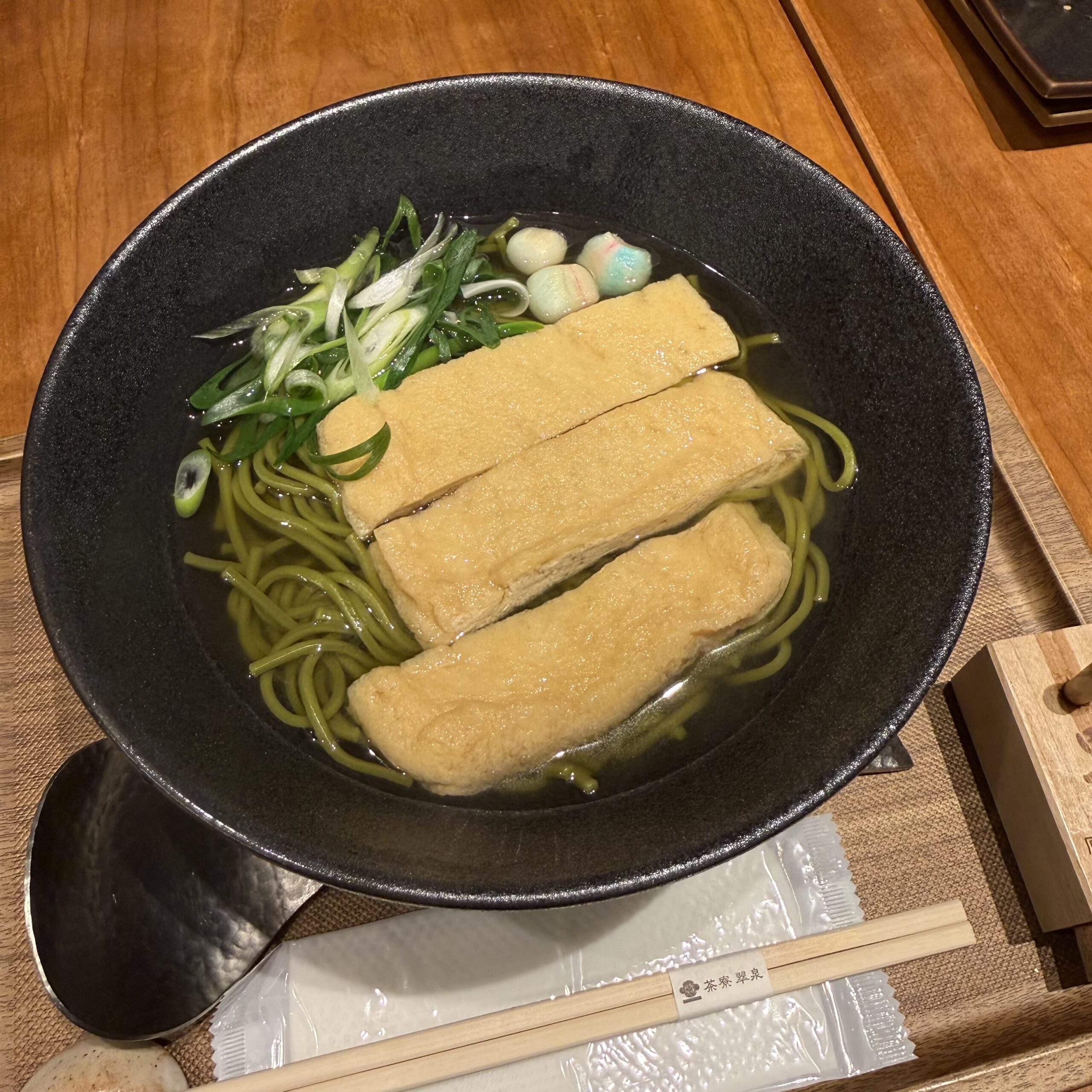 黒い器の茶そば。油揚げ、ネギ、手まり麩。