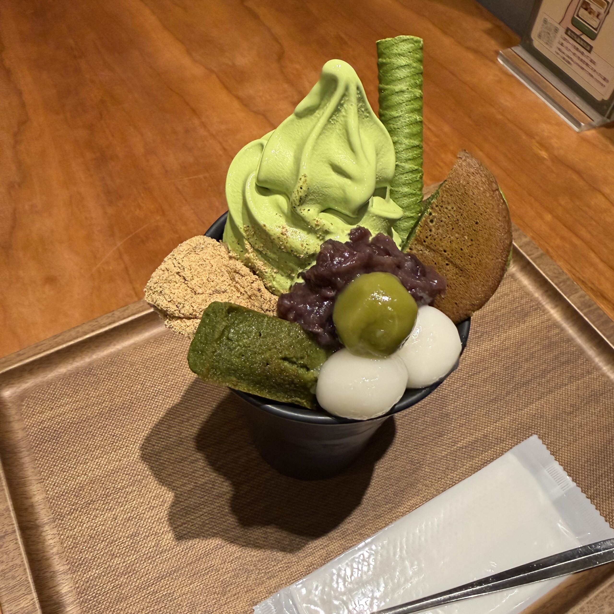 木製トレイの上の、抹茶ソフトとわらび餅が盛られたパフェ。