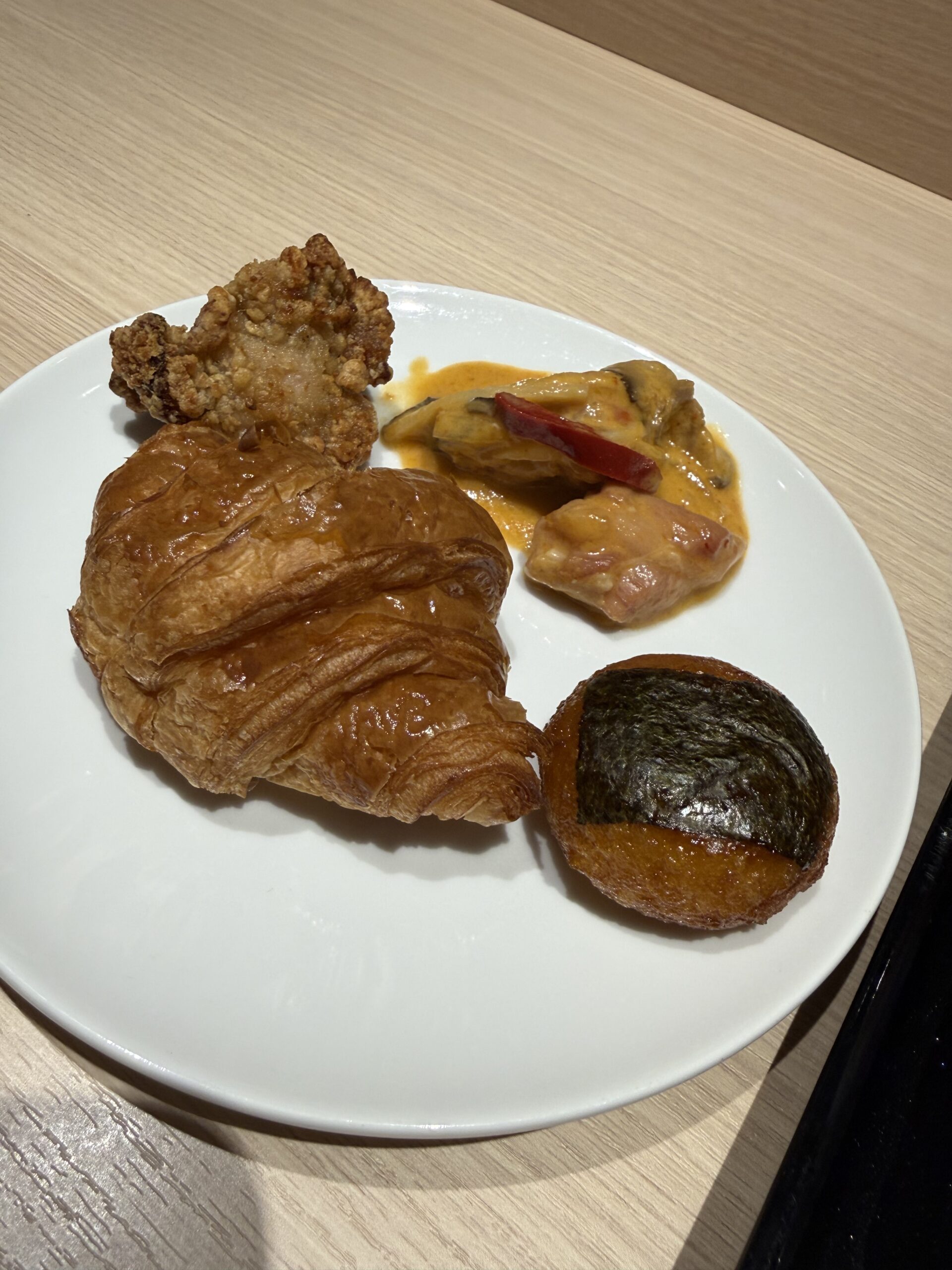 ラウンジの白皿に盛られたパンと和洋のおかず。