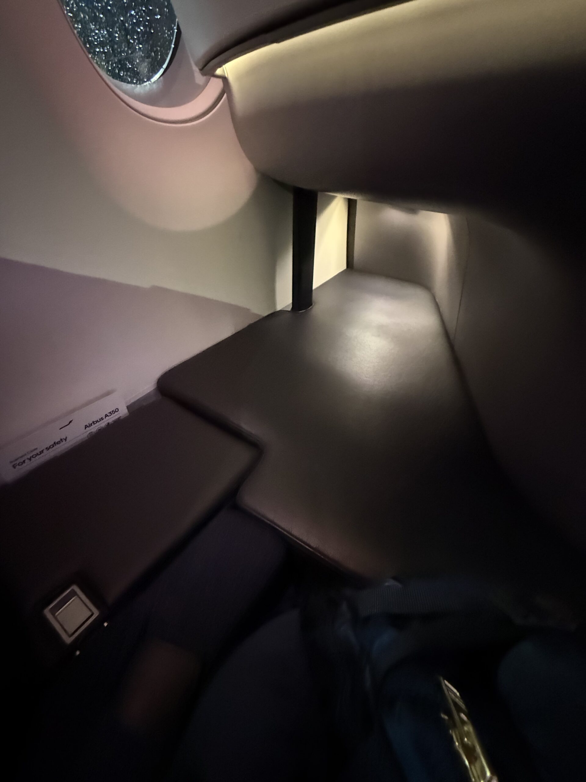 フィンエアーA350ビジネスクラスの足元。窓の雨粒と安全のしおり。