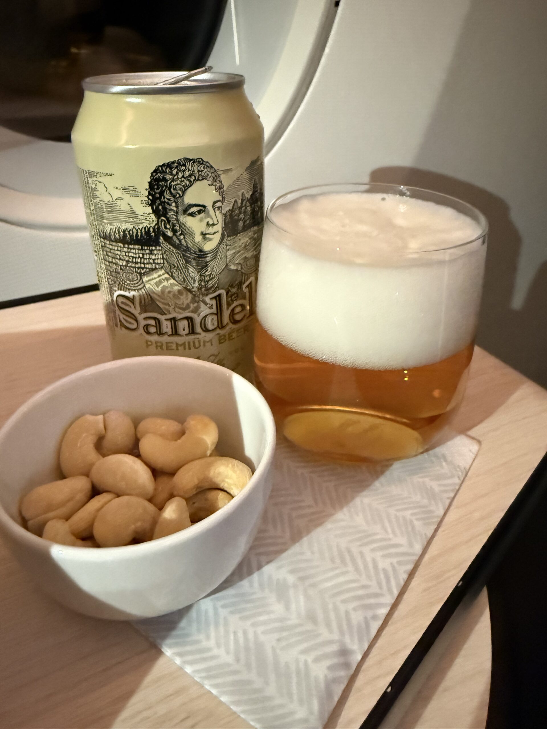 機内のテーブルに置かれたフィンランドビールとカシューナッツ。