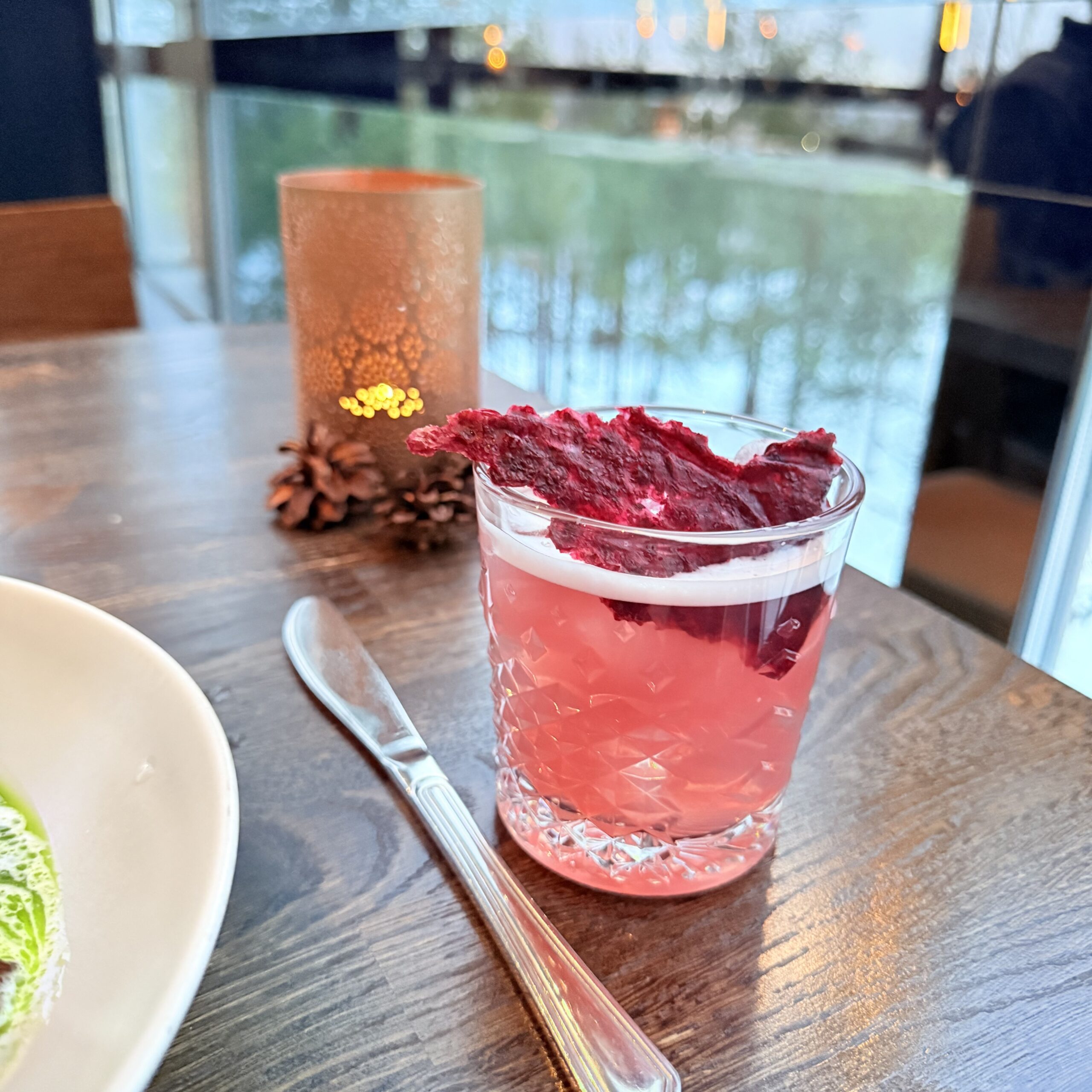ピンク色のモクテルとキャンドル、松ぼっくり