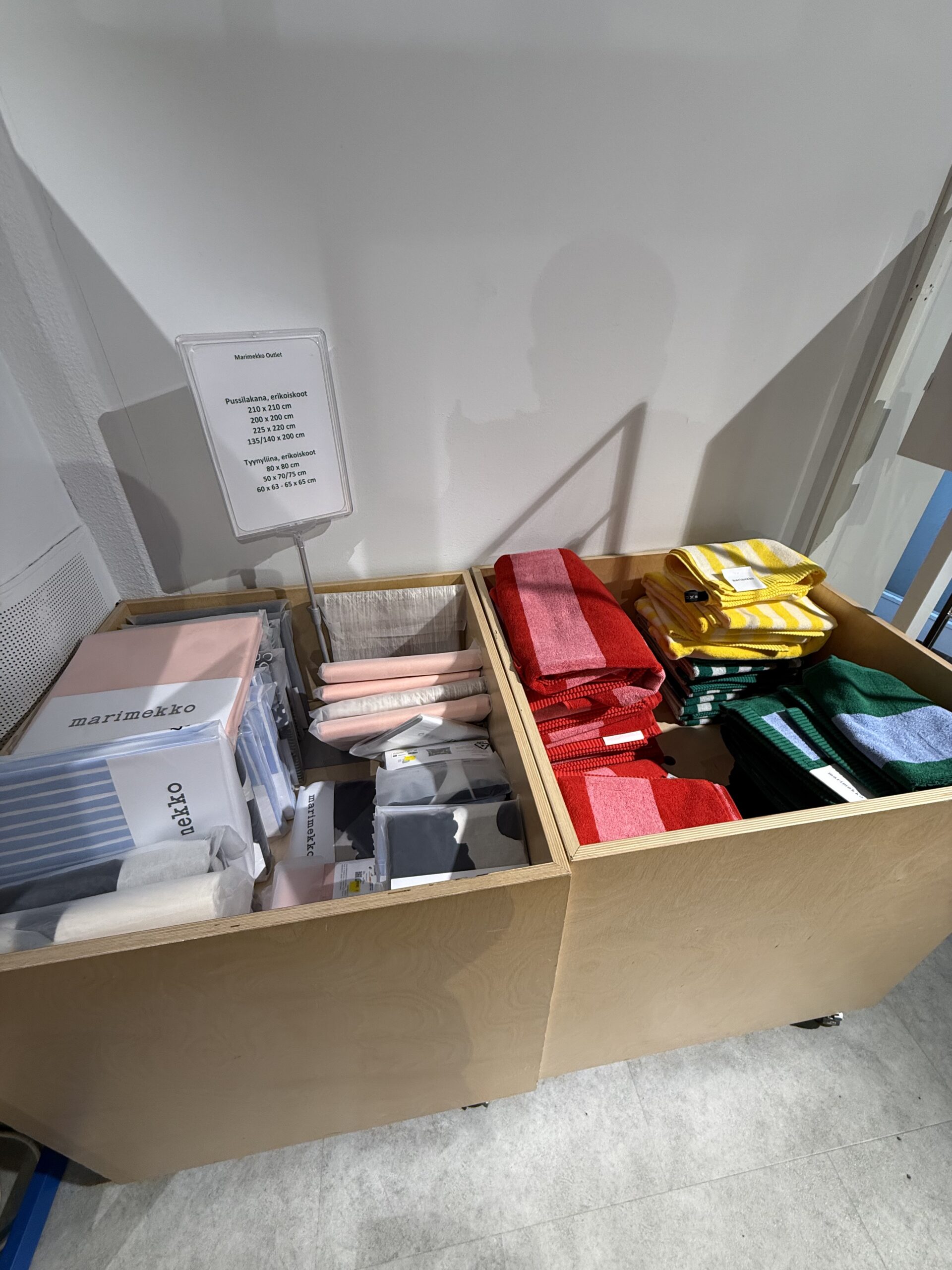 白木の棚に並ぶストライプのタオルとMarimekko Outletのサイン