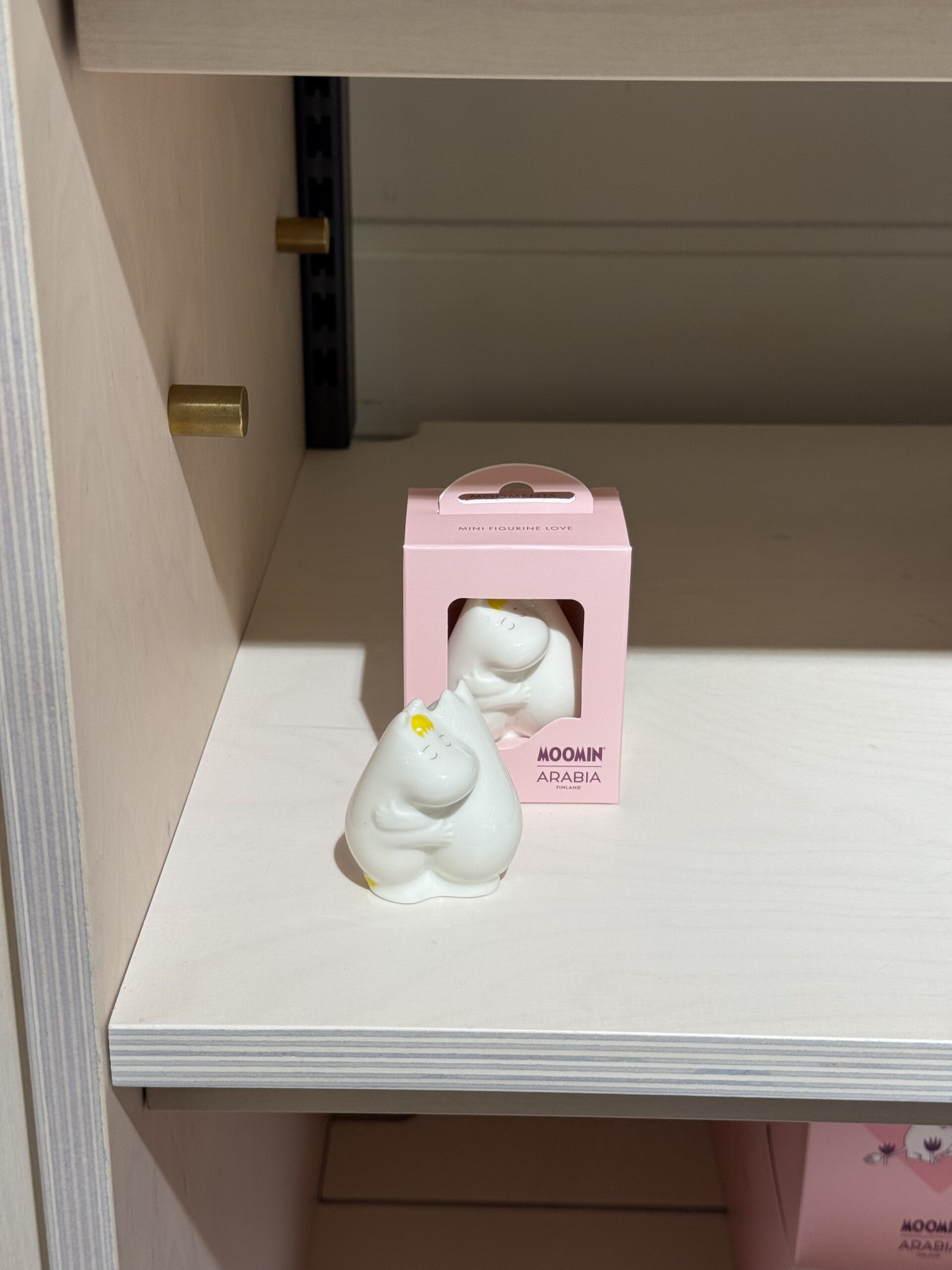 白木の棚に置かれたムーミンのLoveフィギュアとピンクの箱。