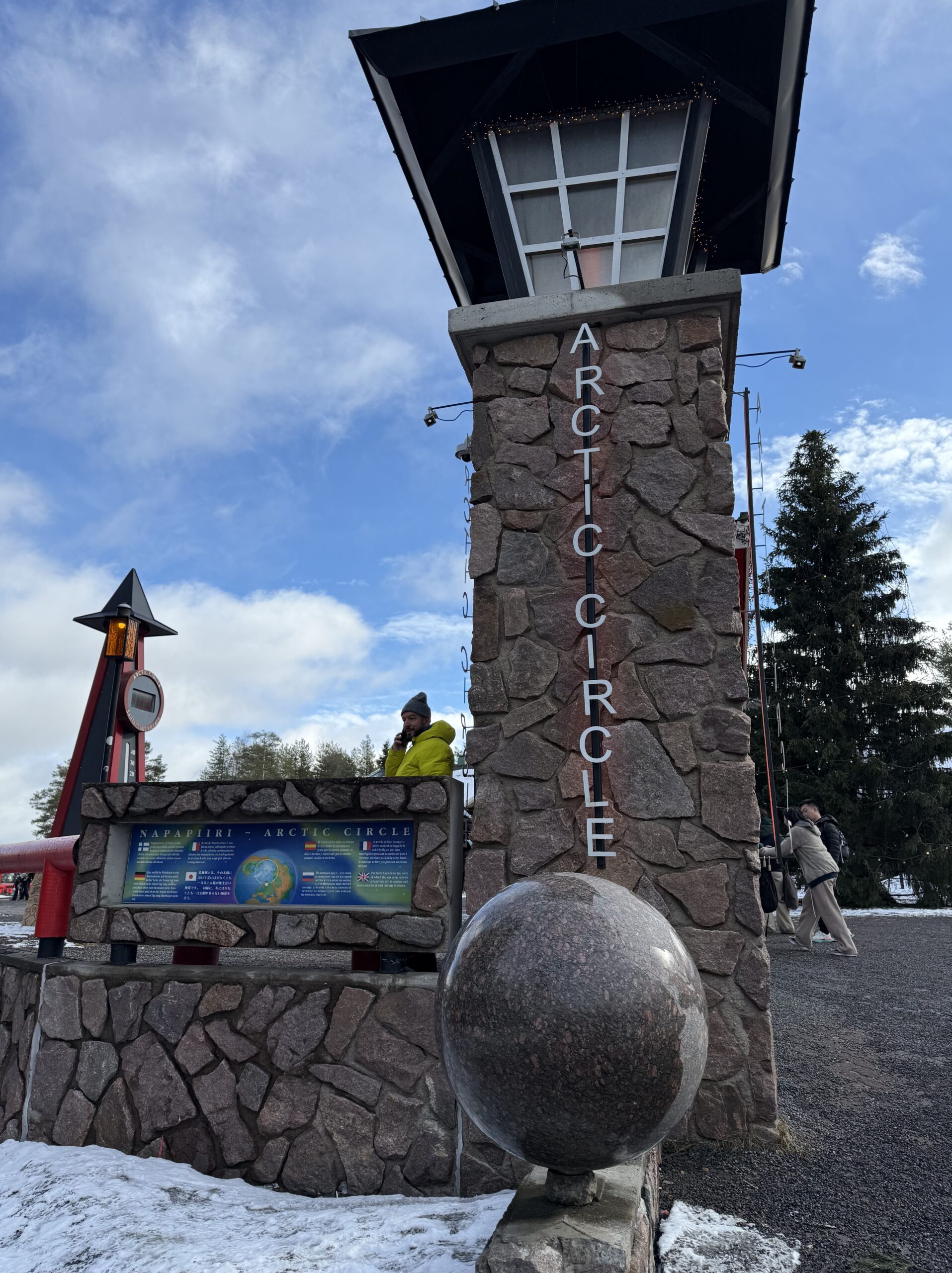 ARCTIC CIRCLEと掲げられたゲートと佇む旅人
