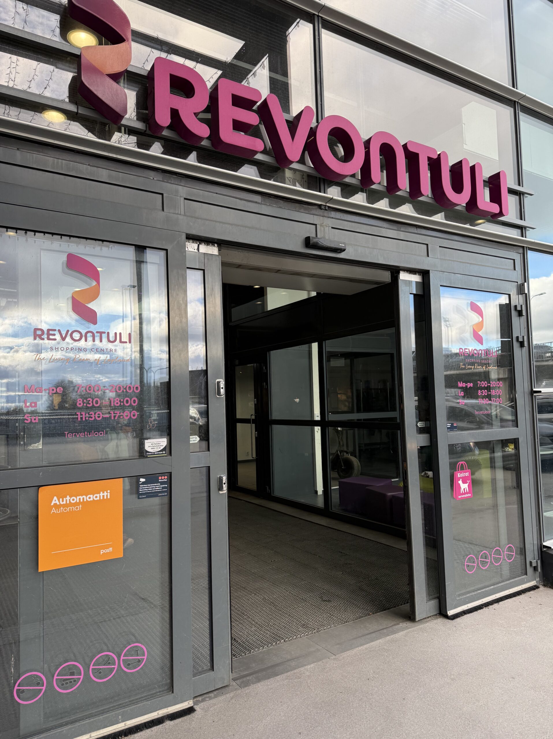 澄んだ空が反射するRevontuliショッピングセンターのガラス張りエントランス