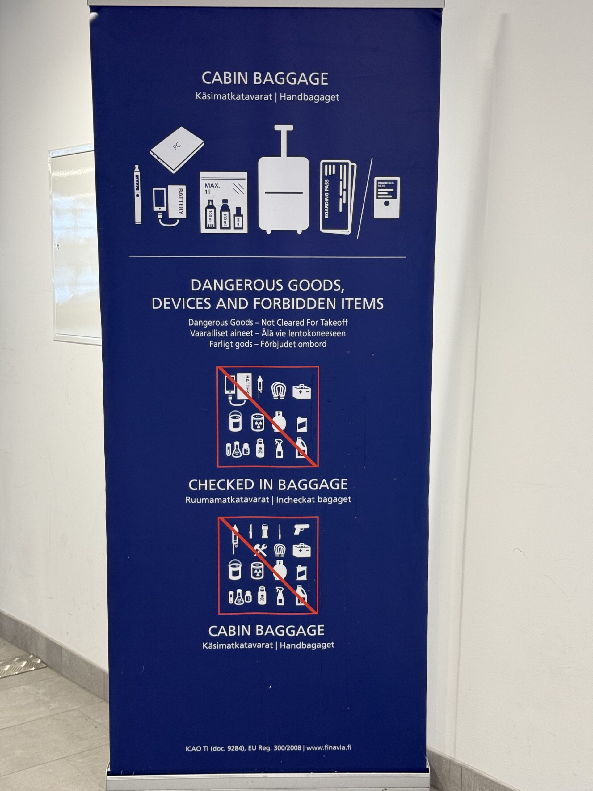 保安検査場へと向かう道すがらに立つネイビーブルーの手荷物ルール案内サイン