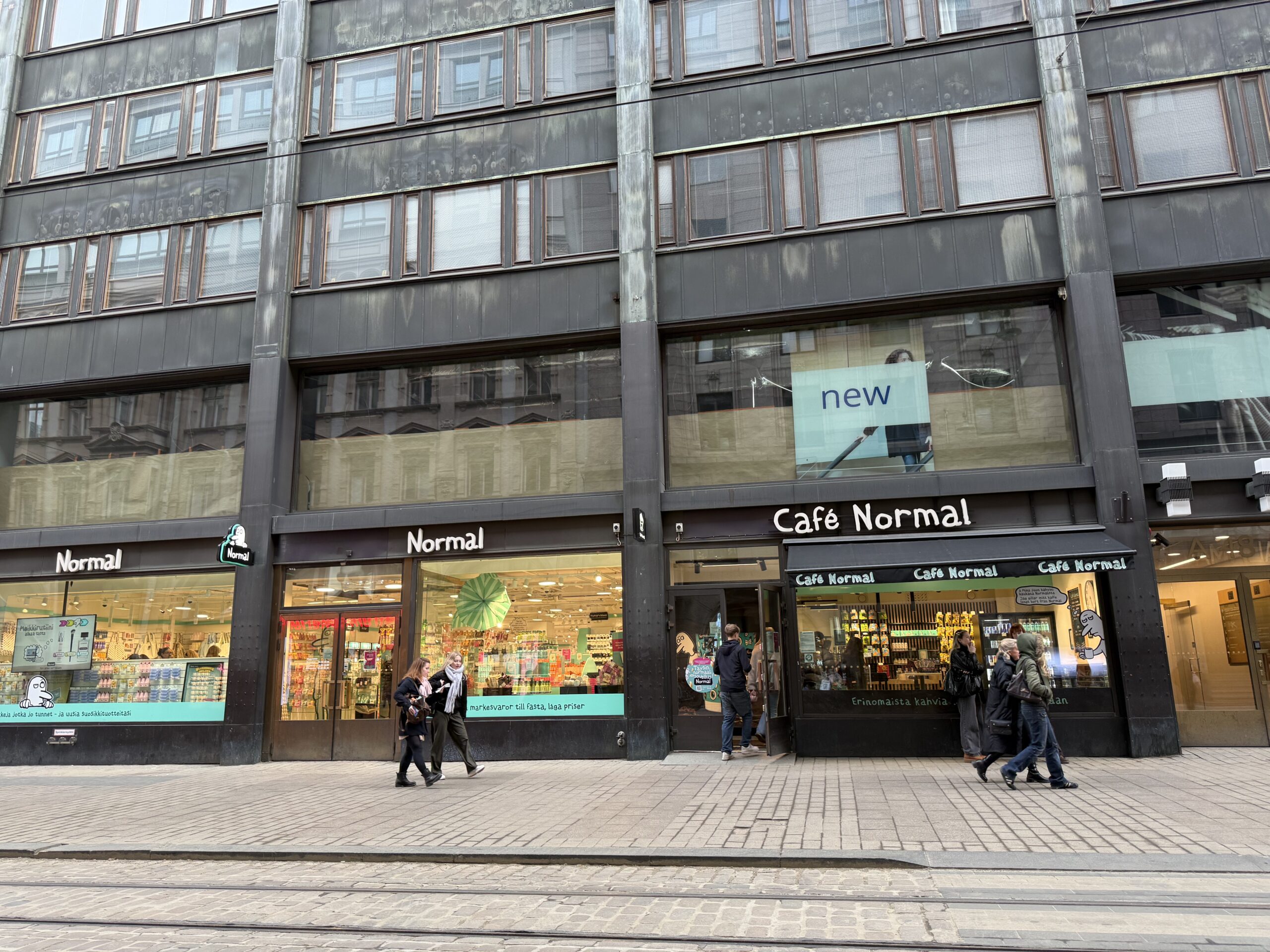 Bright signs of Normal and Café Normal on a Helsinki cobblestone street