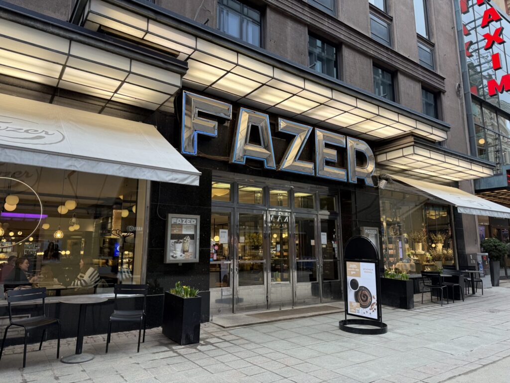 The blue Fazer neon sign glowing warmly against the historic facade