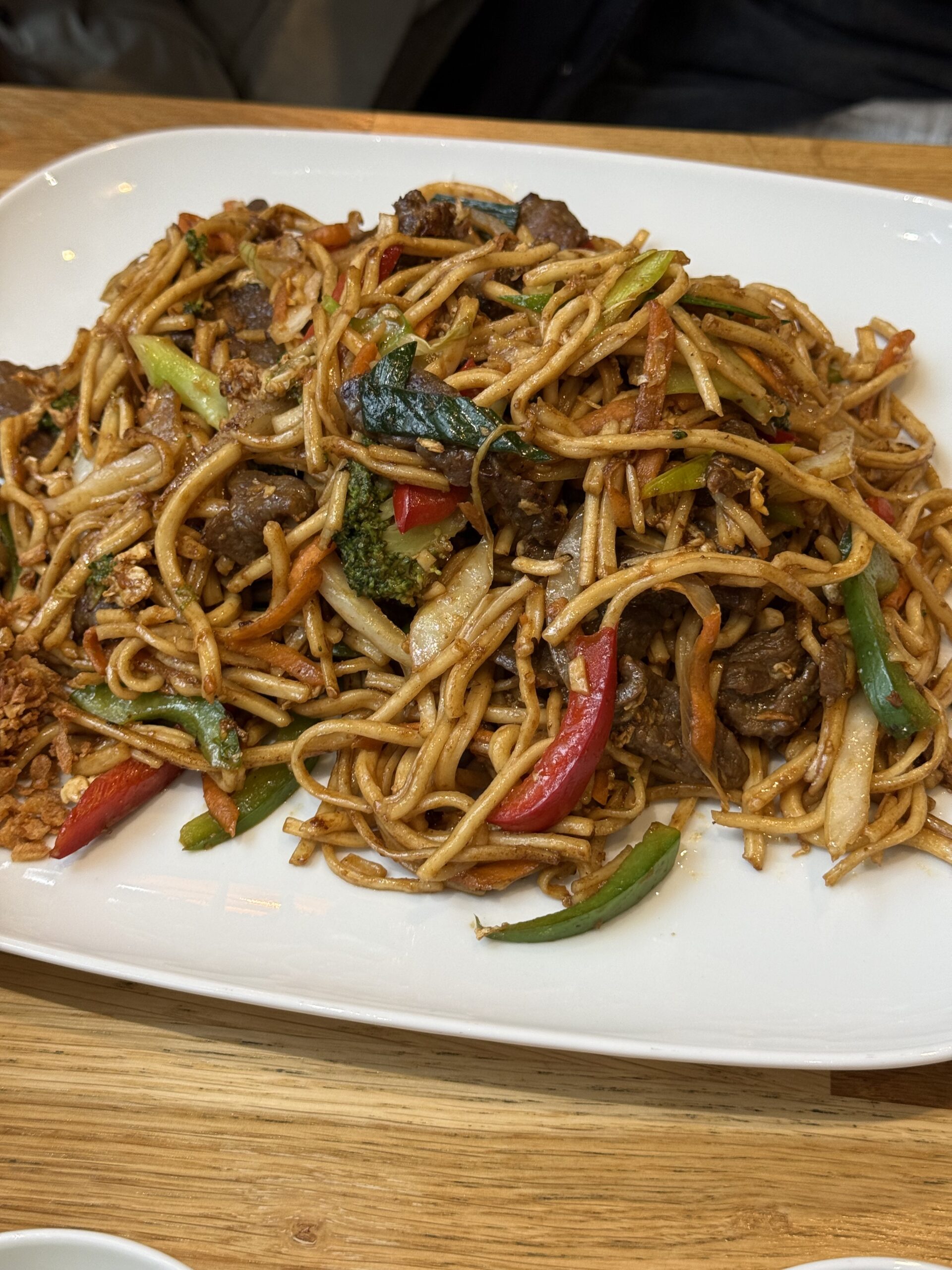 Vietnamese beef fried noodles piled high on a white square plate