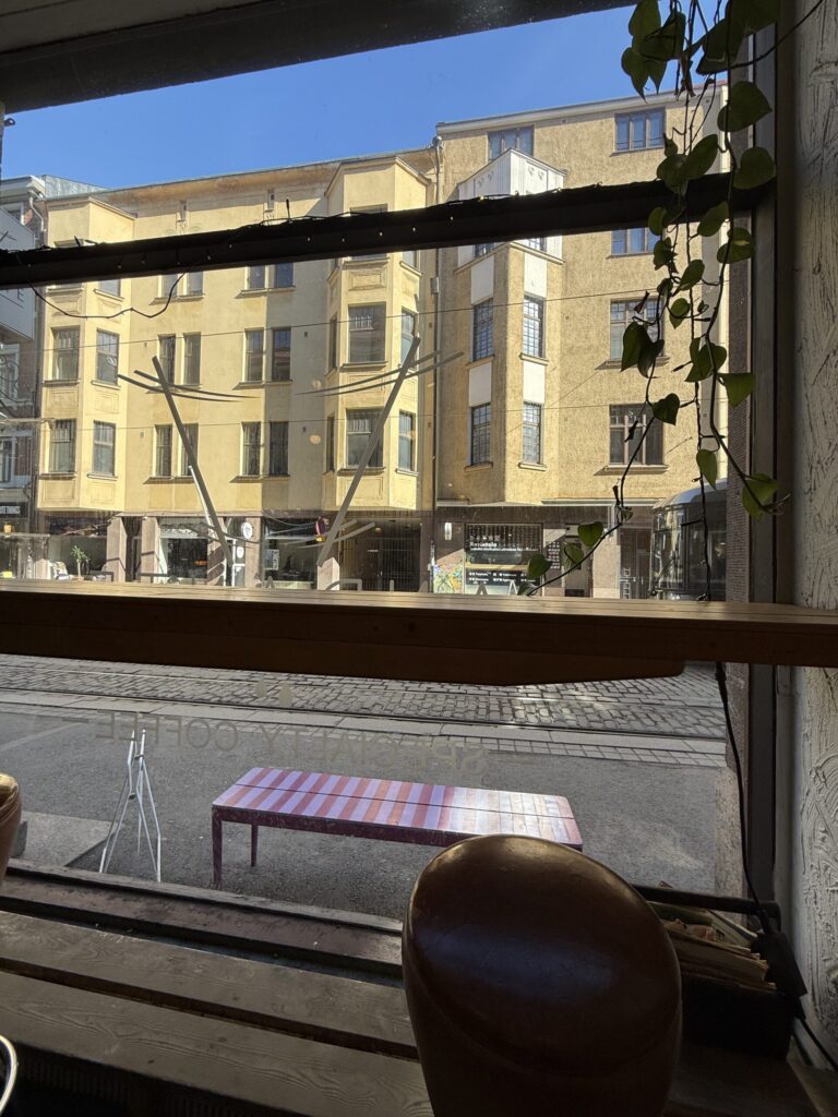 View from the window seat at the cafe showing a sunny street and a yellow building.