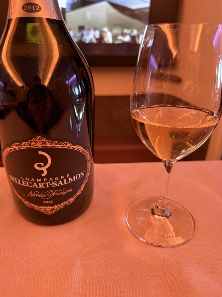 A beautifully poured glass of champagne next to the bottle