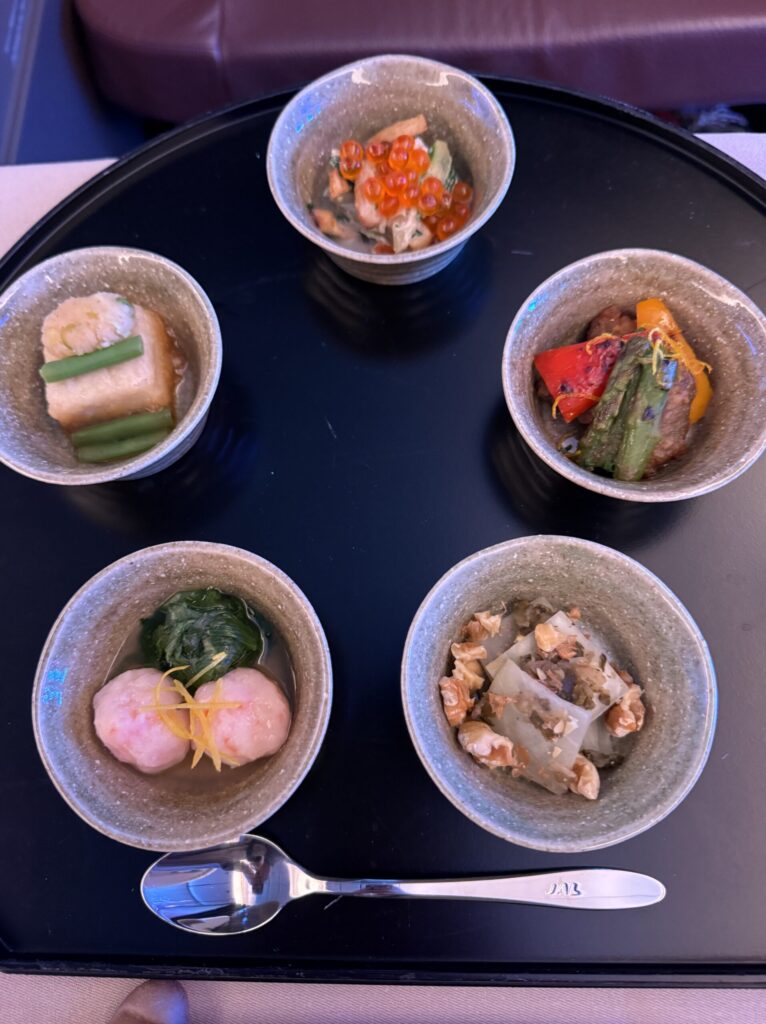 黒い丸盆に並ぶ和食の小鉢五品