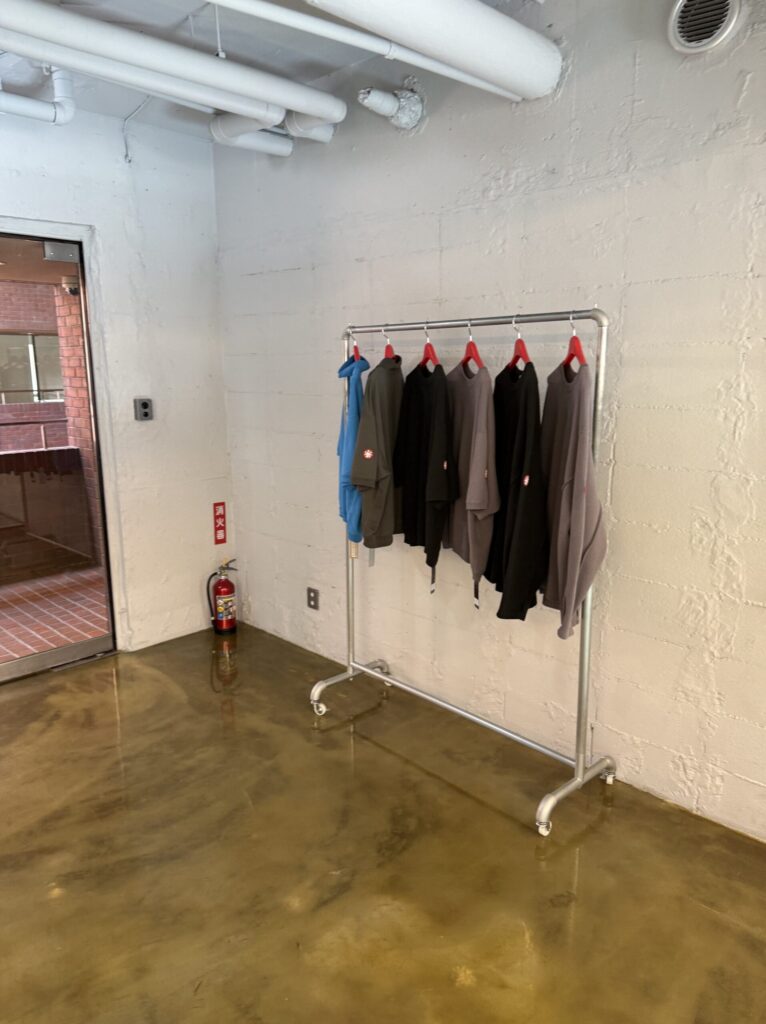 Industrial metal rack displaying C.E apparel with the iconic red silicone patch