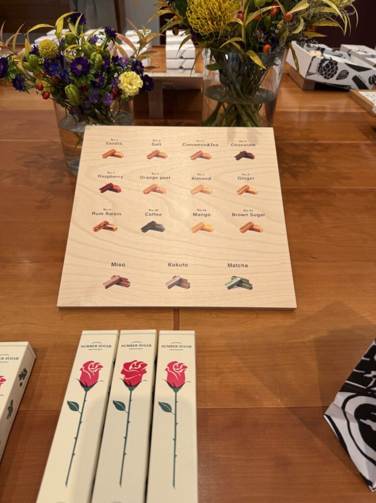 Wooden menu board listing numbered caramel flavors next to fresh flowers