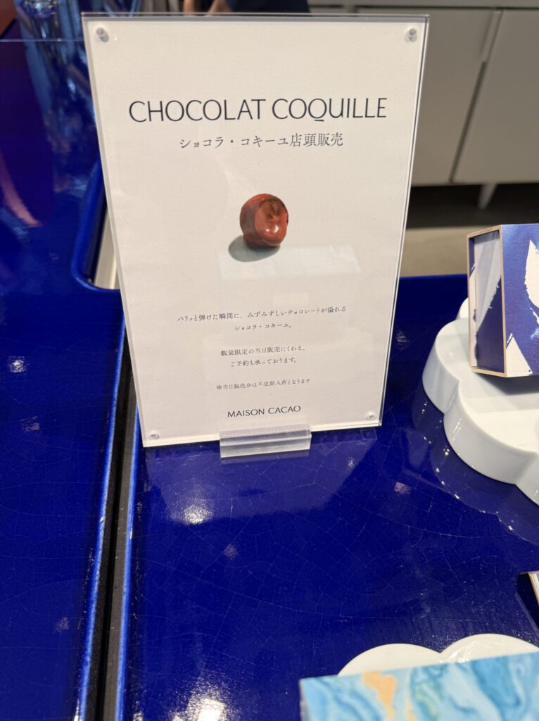 Pop-up sign introducing Chocolat Coquille on a blue tiled surface