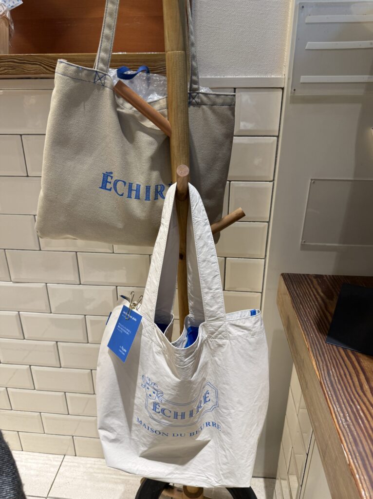 A canvas tote bag featuring the vibrant blue Echire logo hanging on the wall