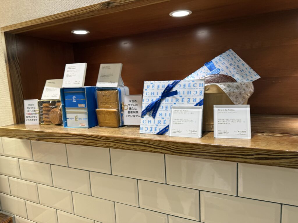 Blue and white tins resting under downlights with a limit sign on the shelf
