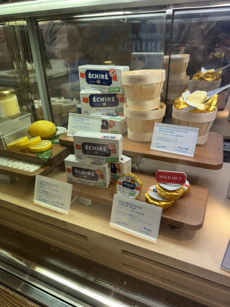 Pristine white and blue butter packages alongside fresh lemons in the glass case