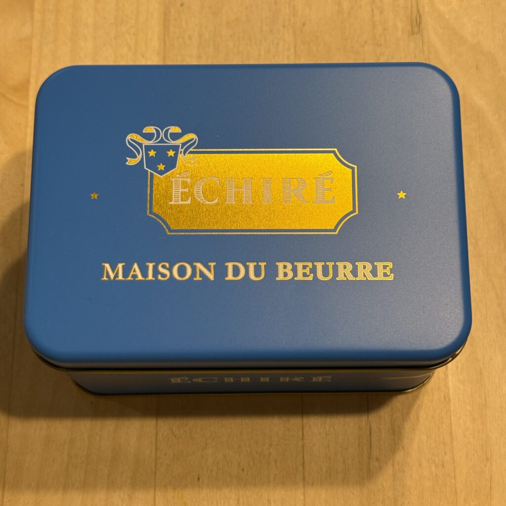 A striking French blue tin with gold foil lettering resting on a wooden table