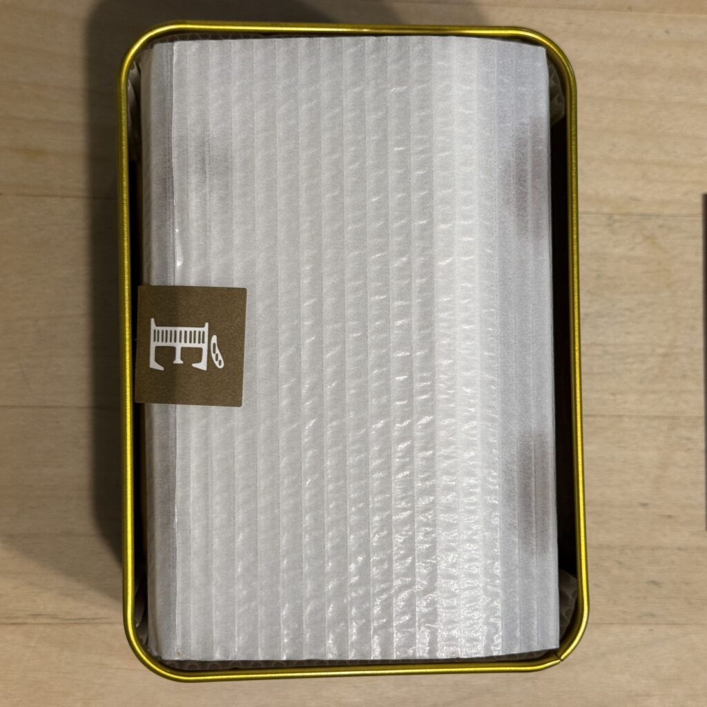 Pure white cushion paper secured by a chic sticker with the E logo inside the tin