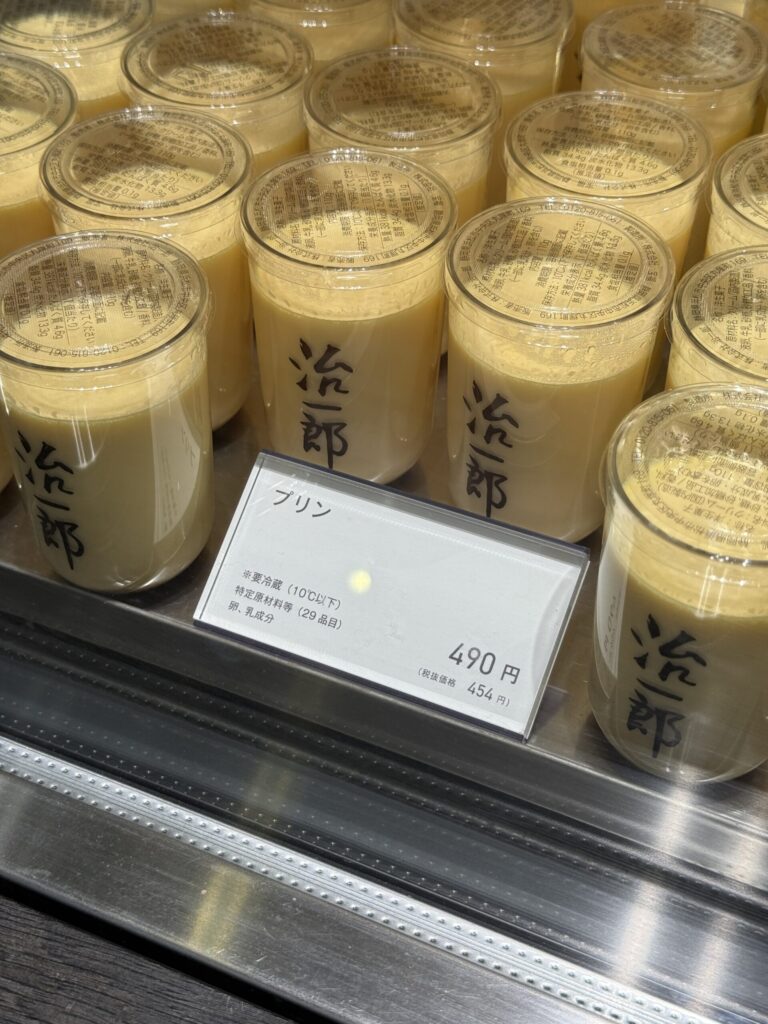 Close-up of golden Jiichiro puddings in a chilled showcase with a price tag of 490 yen