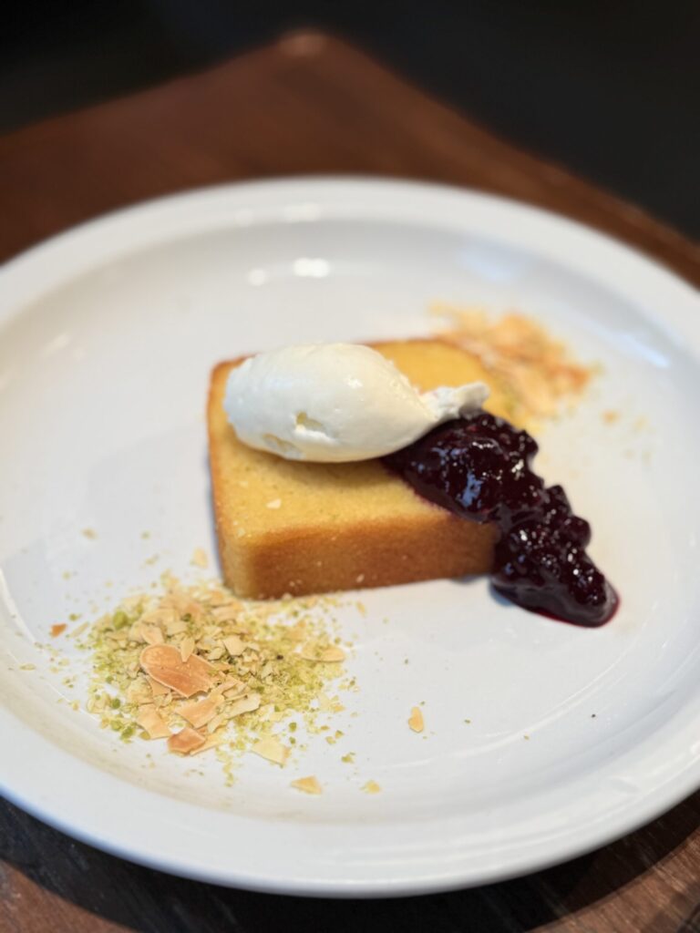 A baked cake topped with fresh cream and berry sauce